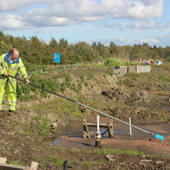 <span class=heading><b>Unearthing the potential beneath</b> by Keith Torrance</span><br />In partnership with Scottish Canals, Strathclyde researchers are aiming to transform noxious, wet canal sediments into useful construction materials, investigating new processes to naturally improve them. One method is to encourage grass and other plants to remove water and break-down any remaining contaminants, improving the texture of the soil. In this photo, we are preparing the surface of a sediment lagoon for over-seeding with a resistant grass variety.<br /><span class=small>Image: © 2021 Keith Torrance</span>.  <span class=small>Collaborators: Richard Lord (photo subject)</span>